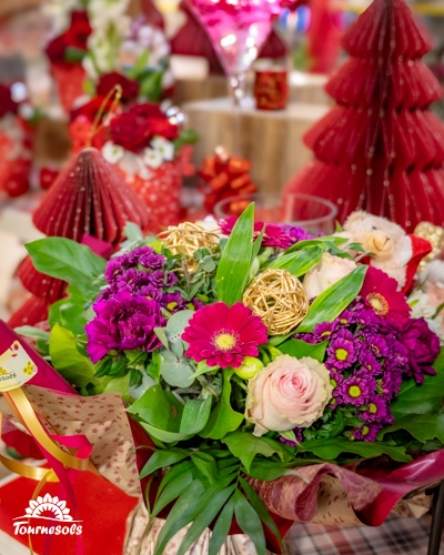 Composition florale avec fleurs rouges et roses, décorée pour Noël.